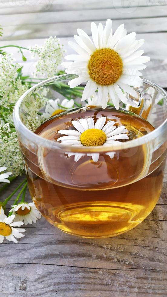 Chamomile aromatic tea in a glass cup on a wooden background. photo