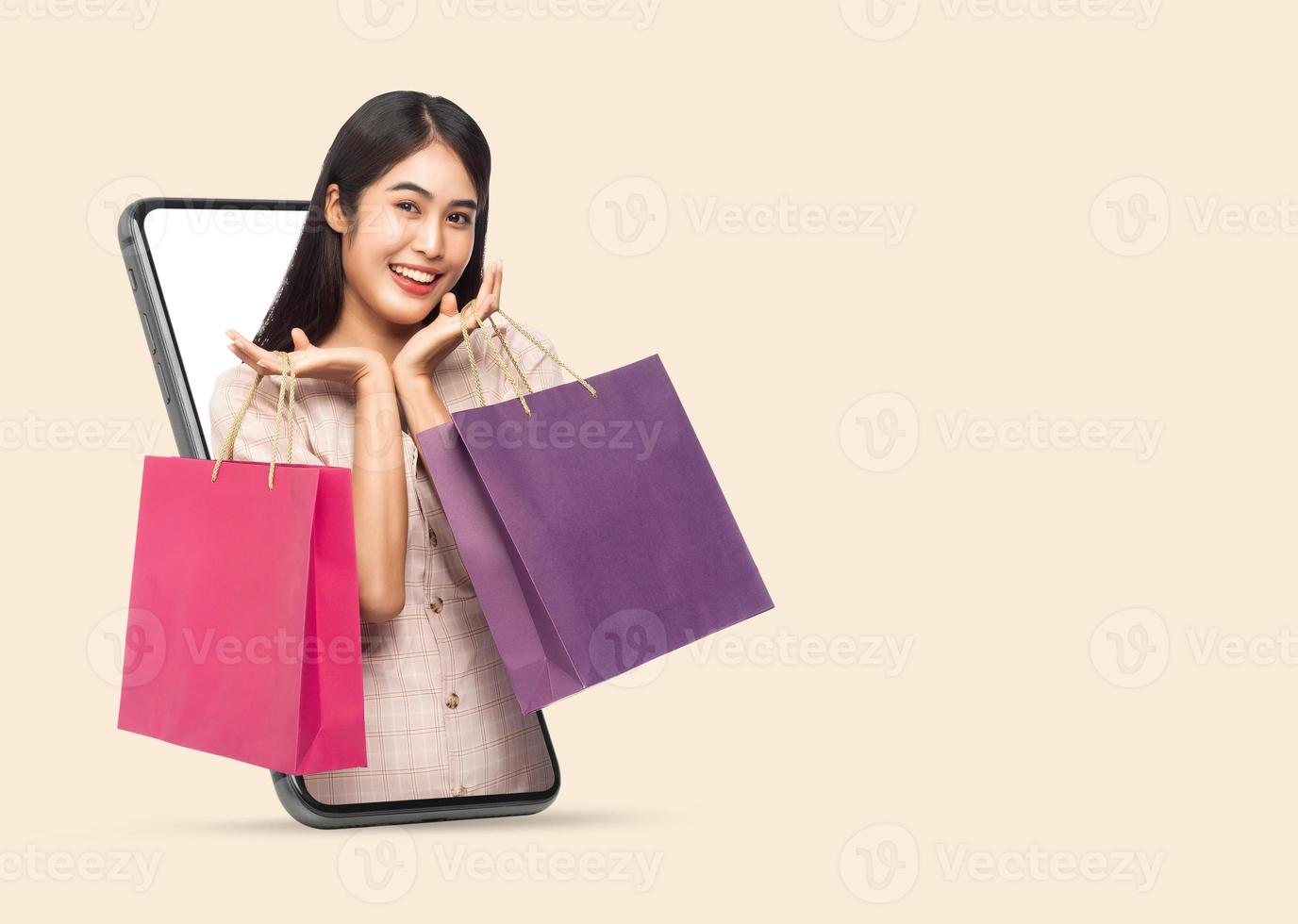 Young woman holding shopping bags via smartphone photo