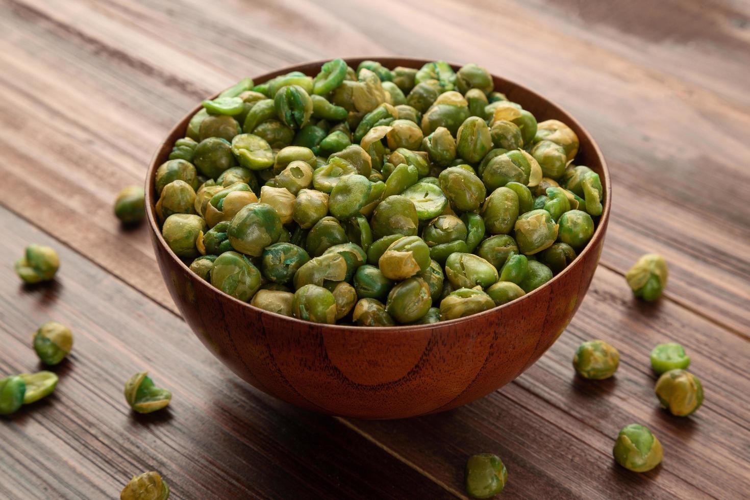 Salted green peas in wooden bowl on the table, Healthy snack photo