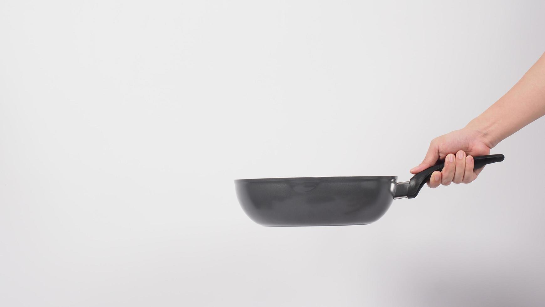 La mano del hombre sobre fondo blanco limpiando la sartén antiadherente foto