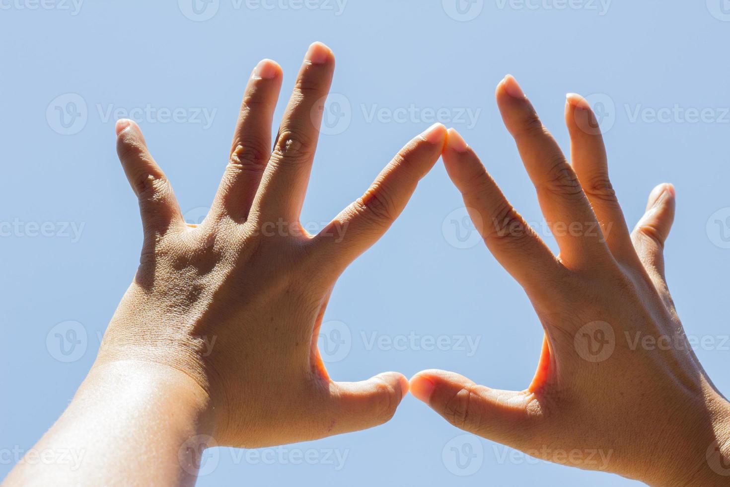 Girl hand in upside down heart form love blue sky photo