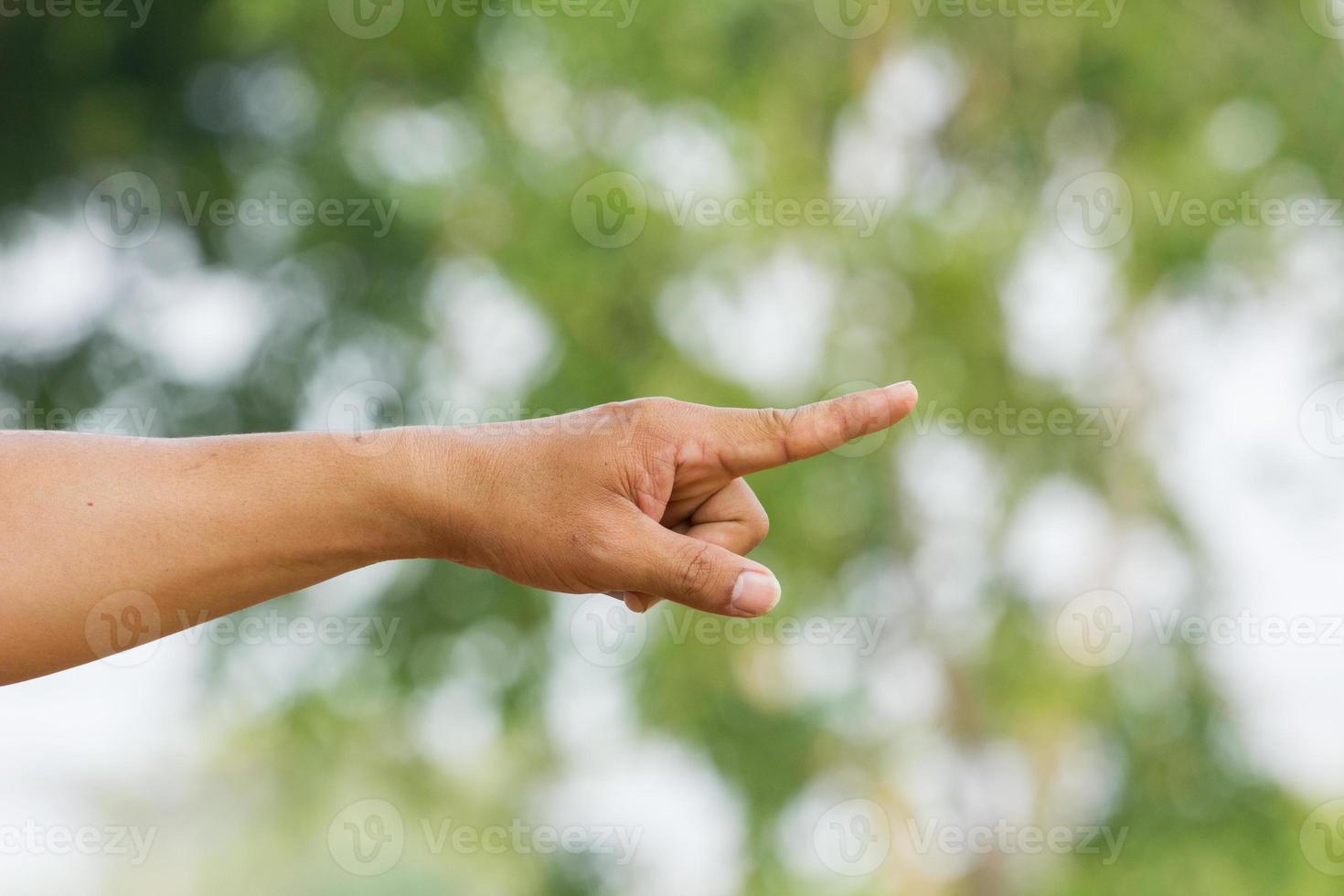 Punto de la mano humana con el dedo en fondo verde con bokeh foto