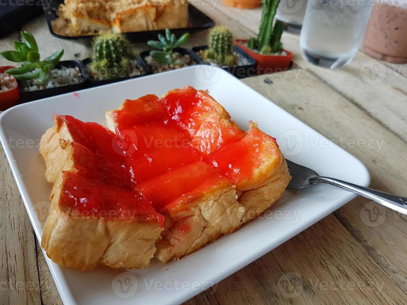 Tostadas con mantequilla y mermelada de fresa sobre fondo de madera foto