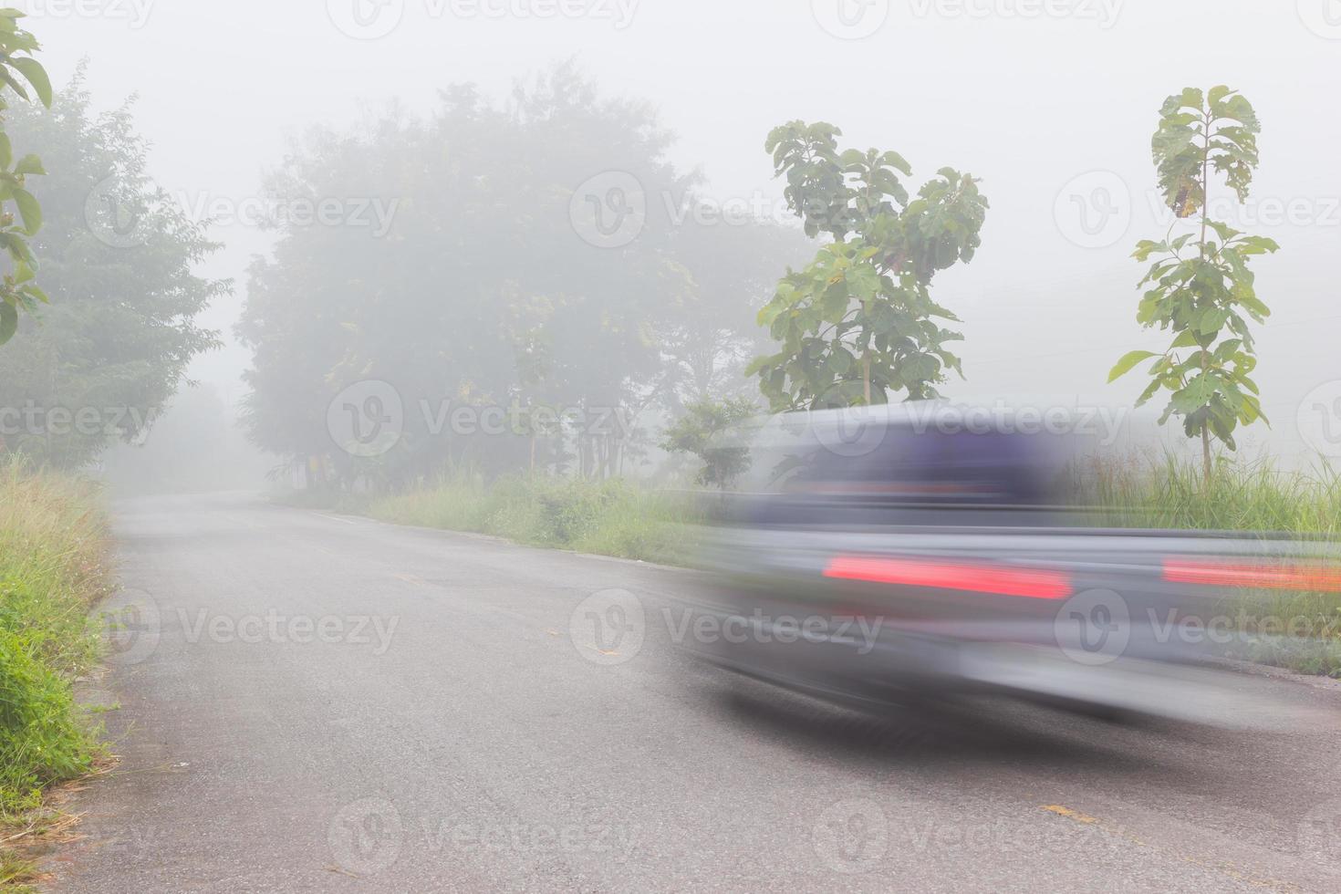 Motion blur of car on road on foggy morning photo