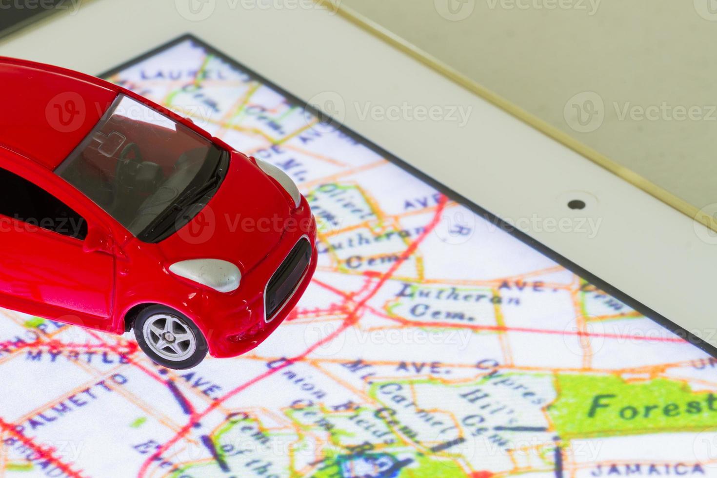 Foto horizontal del primer coche de juguete rojo en el mapa en la pantalla de la tableta