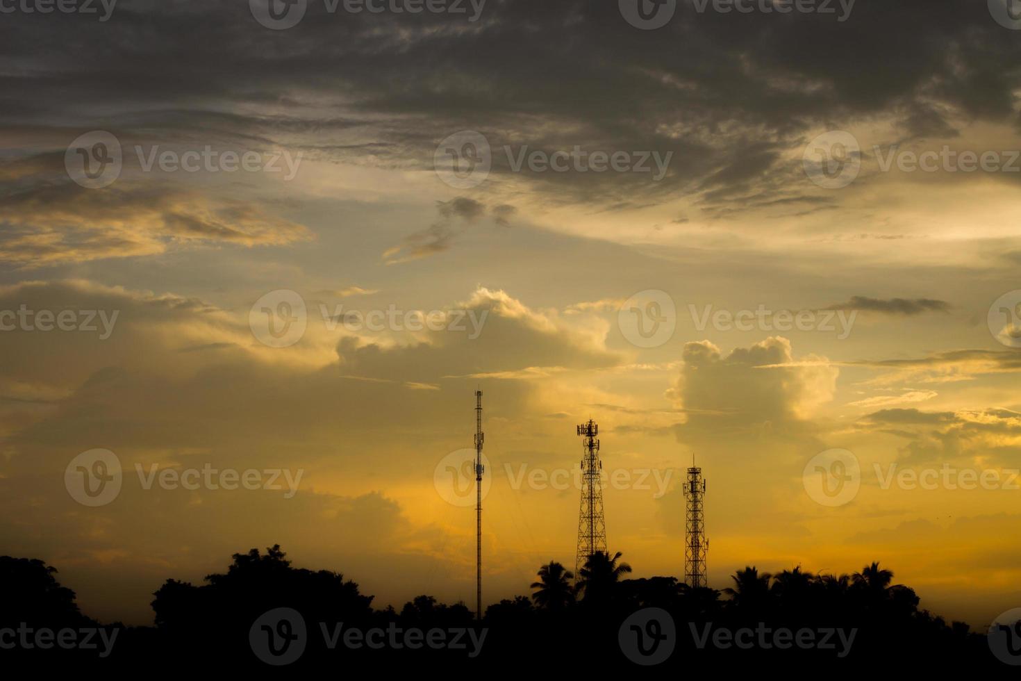 Silhouette communication antennas in evening cloudy sky photo
