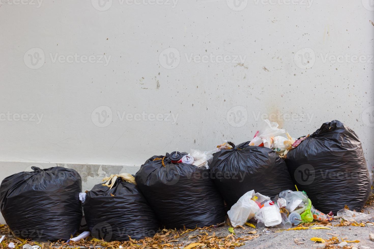 bolsas negras de basura y waiste en la pared sucia en blanco. foto