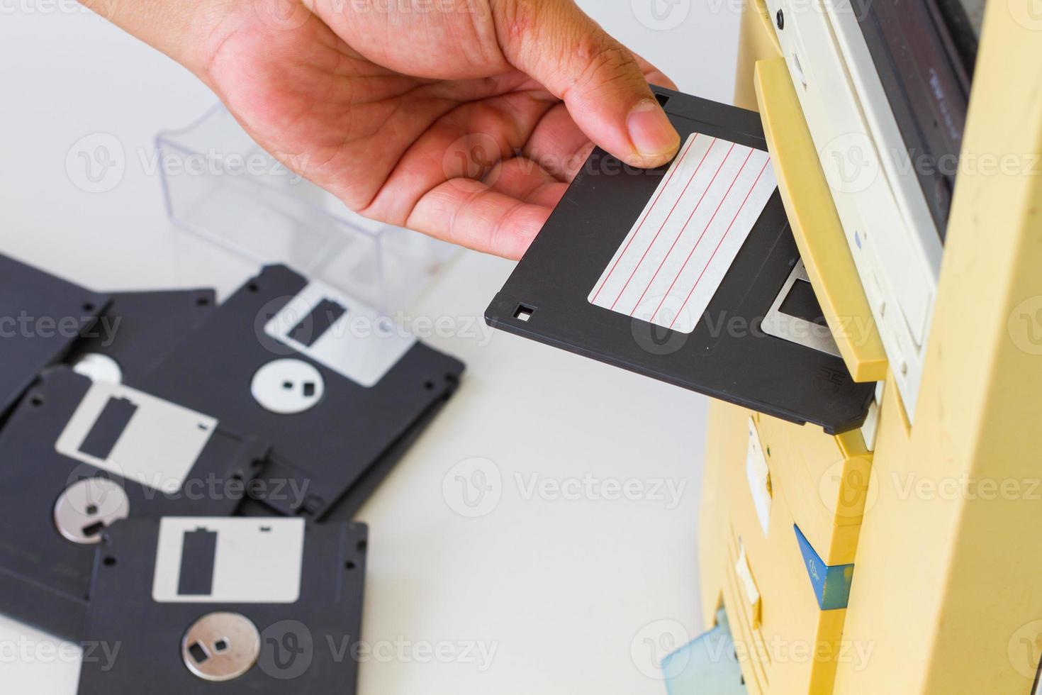 Hand inserting a 3.5-inch floppy disk into a floppy drive photo