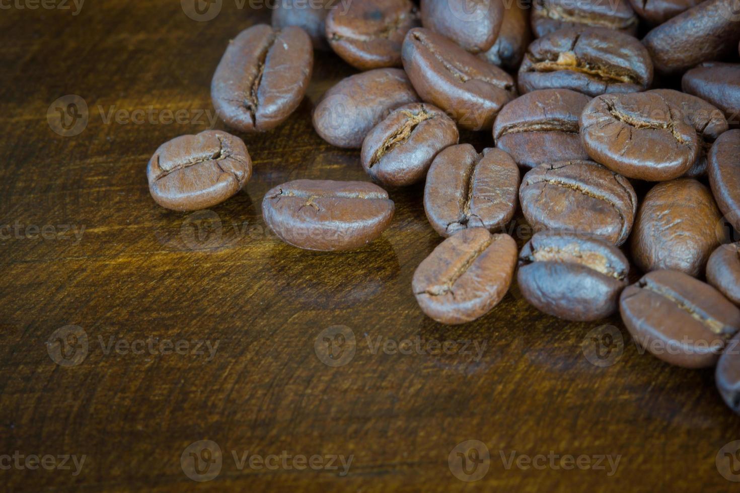 Granos de café de primer plano extrema sobre fondo de madera, tono oscuro foto