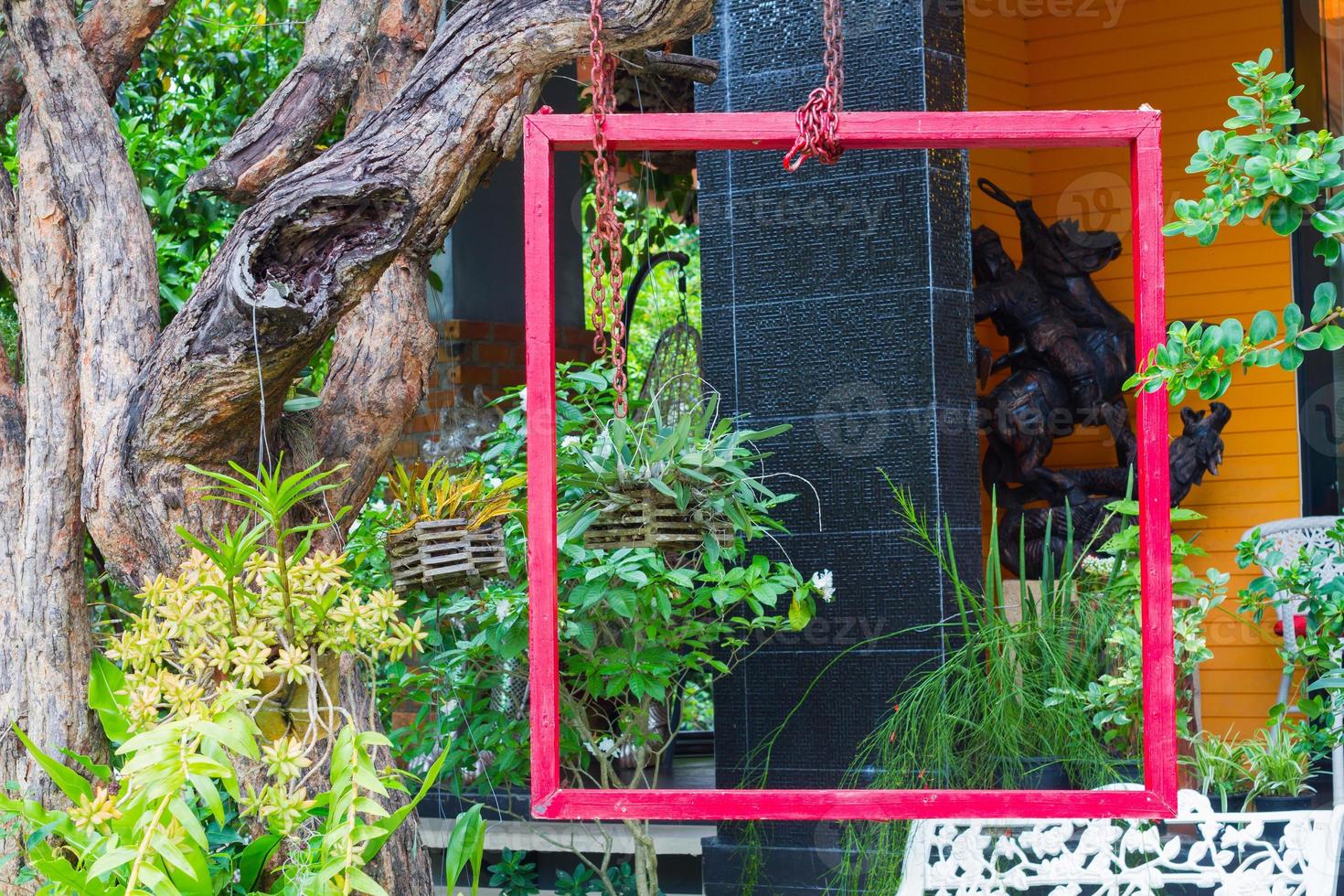 red frame hung on tree in lush garden setting photo