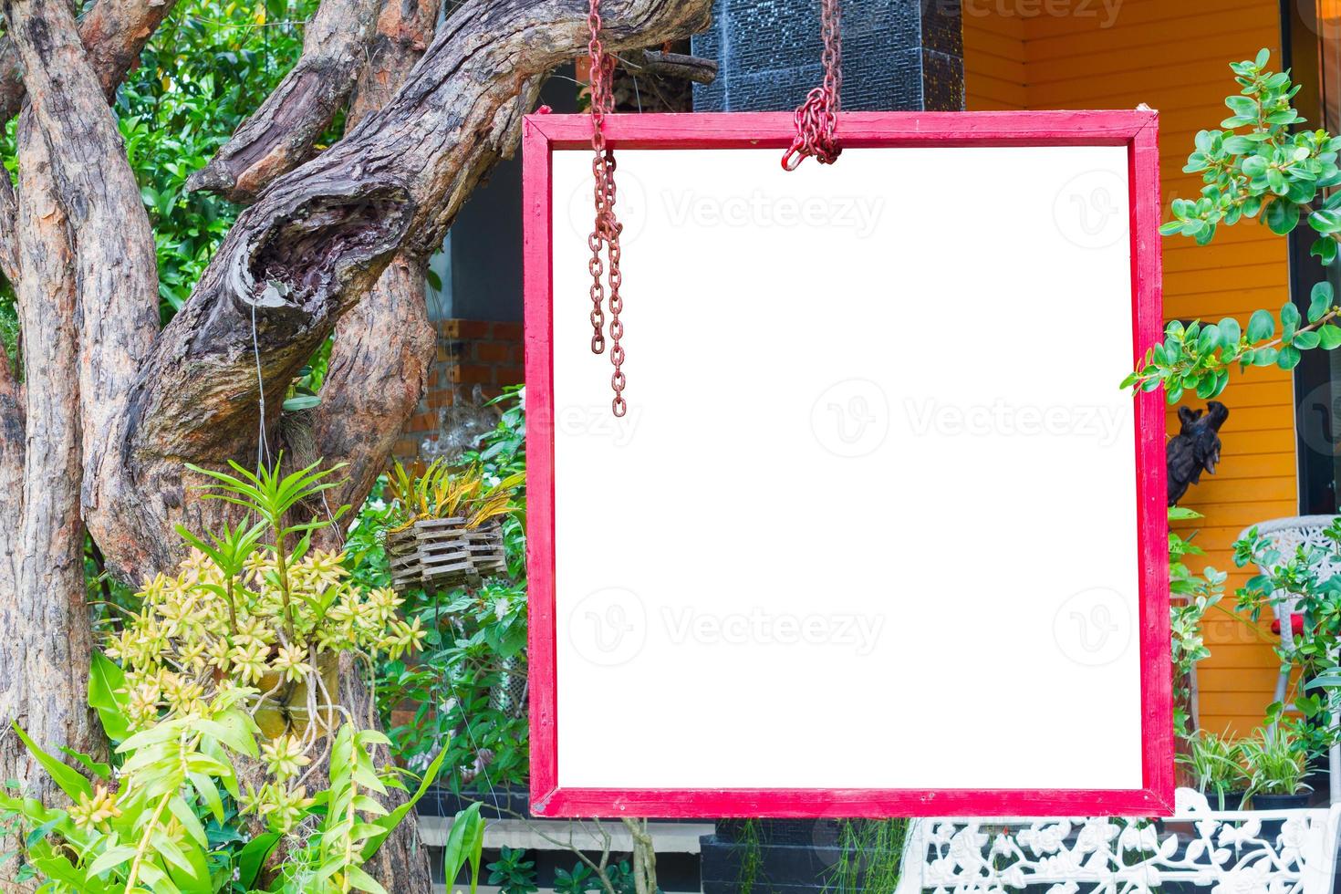 marco rojo aislado colgado de un árbol en un jardín exuberante, trazado de recorte. foto