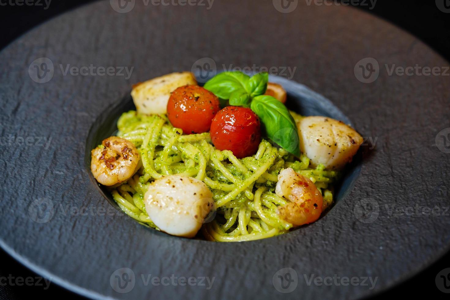 Conchas de agua salada fritas sobre espaguetis con pesto verde foto