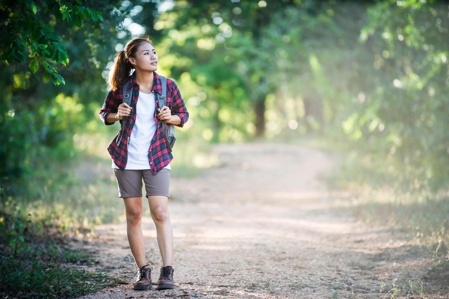 Joven excursionista con mochila caminando y sonriendo por un sendero campestre foto