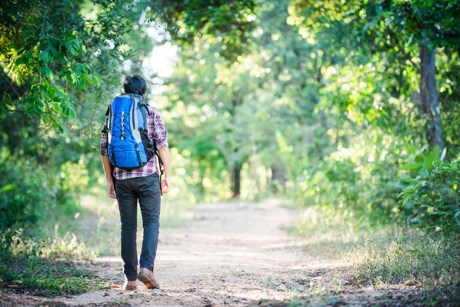 Hombre joven inconformista caminando por el camino rural durante caminatas de vacaciones. foto