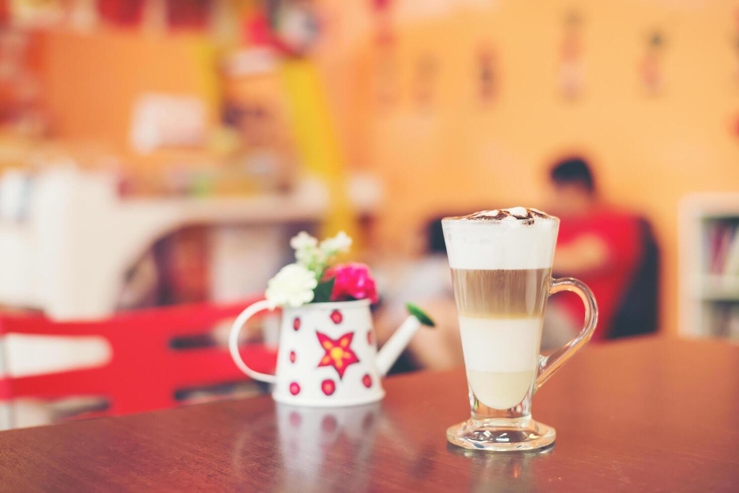 Cup of coffee with flower lobe pattern in reveal cup on wooden table. photo