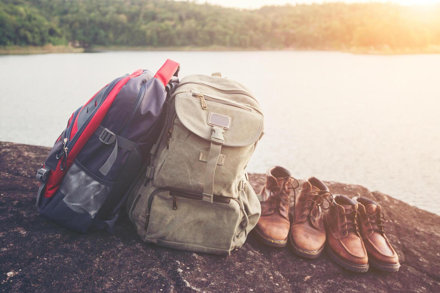 Backpacks and shoes with nature lake background. photo