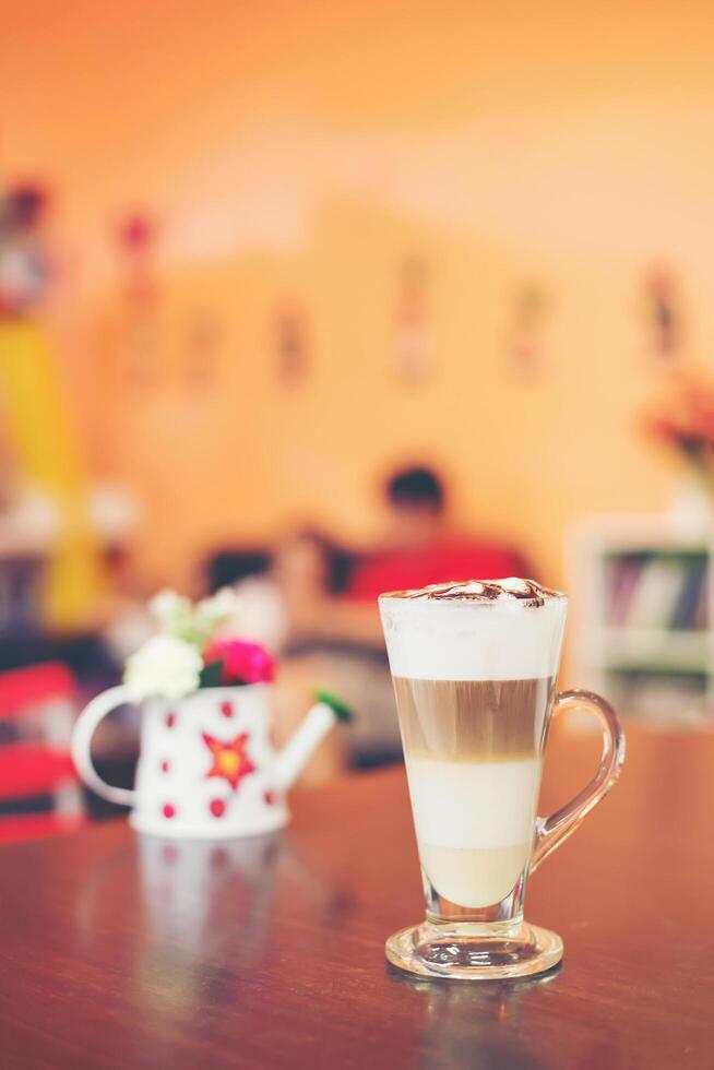 Cup of coffee with flower lobe pattern in reveal cup on wooden table. photo