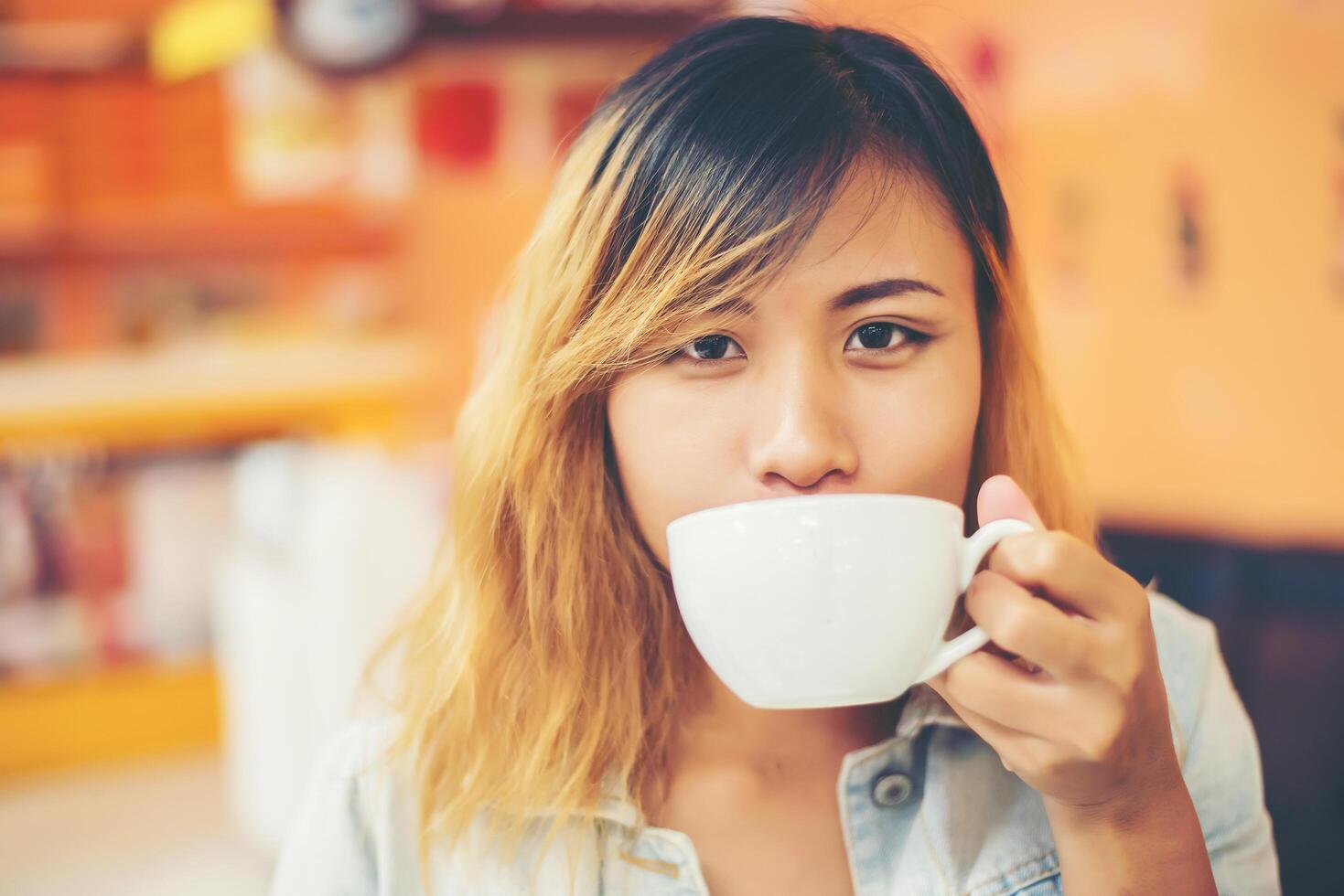 Young beautiful woman drinking hot cappuccino coffee at cafe. photo