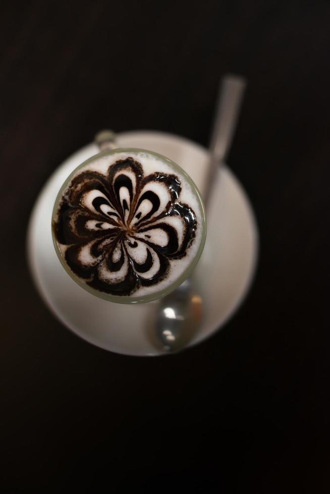 Taza de café con patrón de lóbulos de flores en taza reveladora sobre mesa de madera. foto