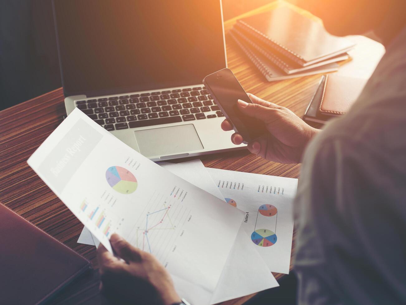 Businessman hands using cell phone with financial report graph. photo