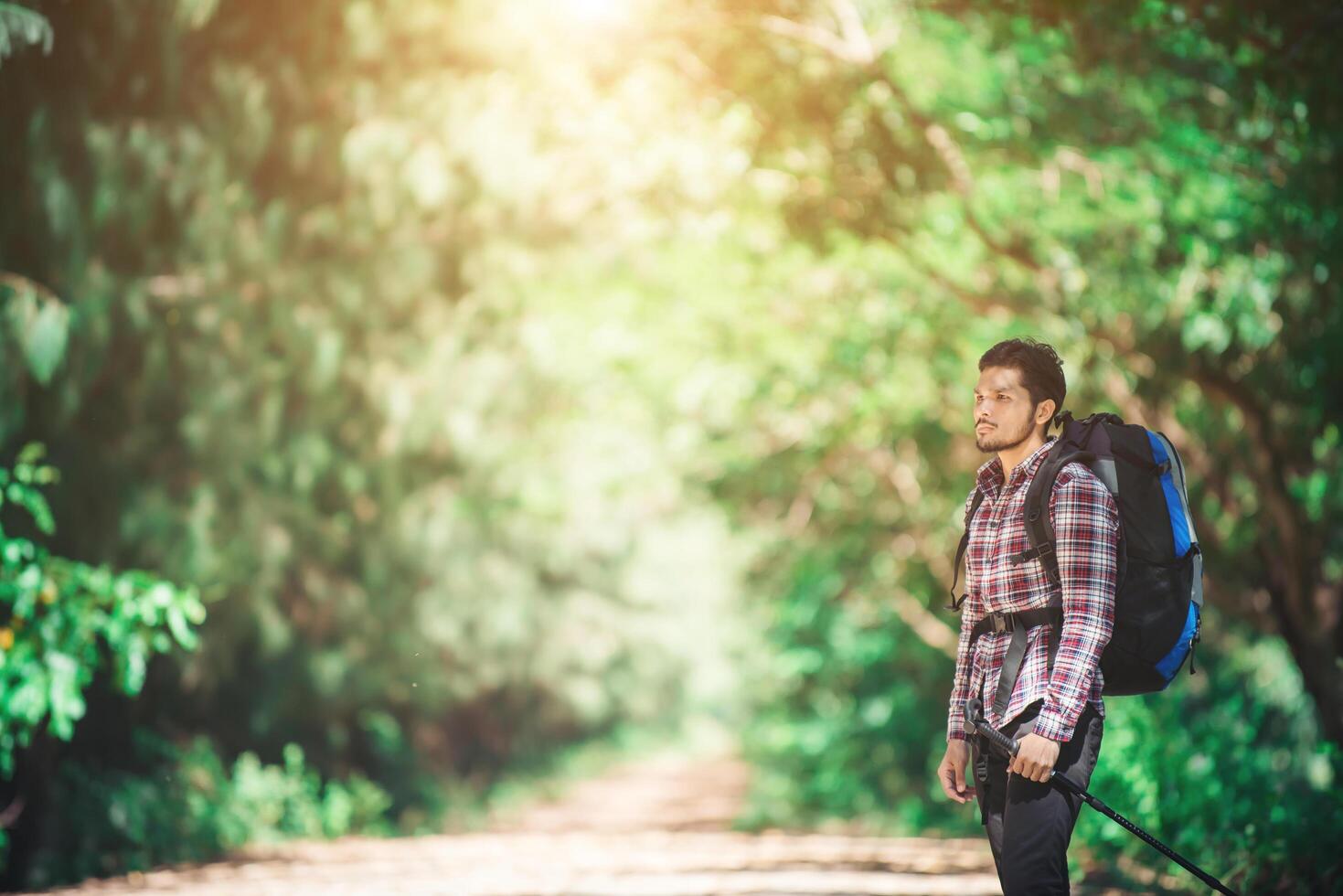 Hipster man hiker holding poles and looking away. photo