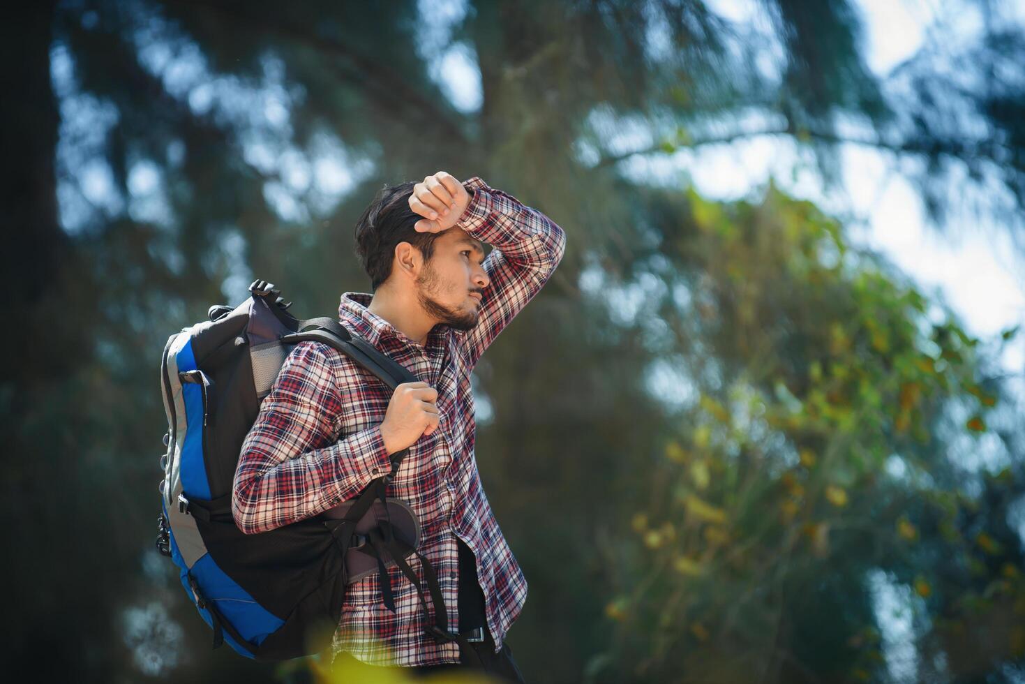 Tired hiker man with a large backpack during walk in the forest