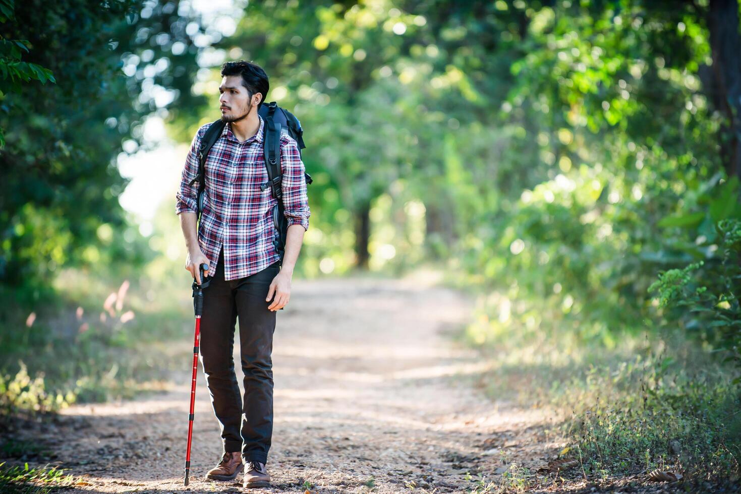 Hombre joven inconformista caminando por el camino rural durante caminatas de vacaciones. foto