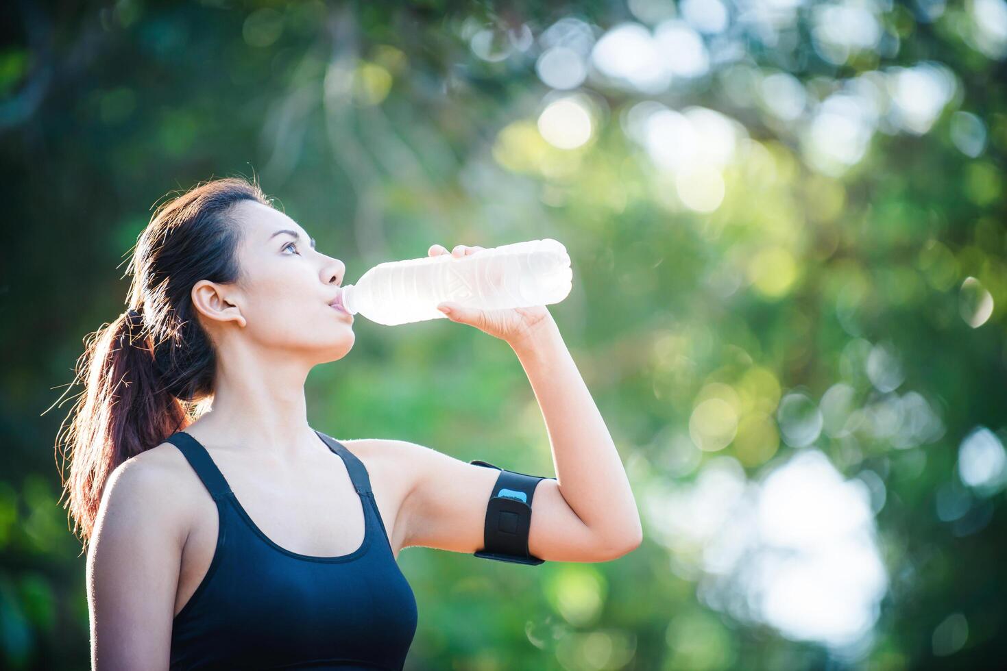 mujer joven tomando un descanso durante la carrera. bebiendo agua de botella. foto