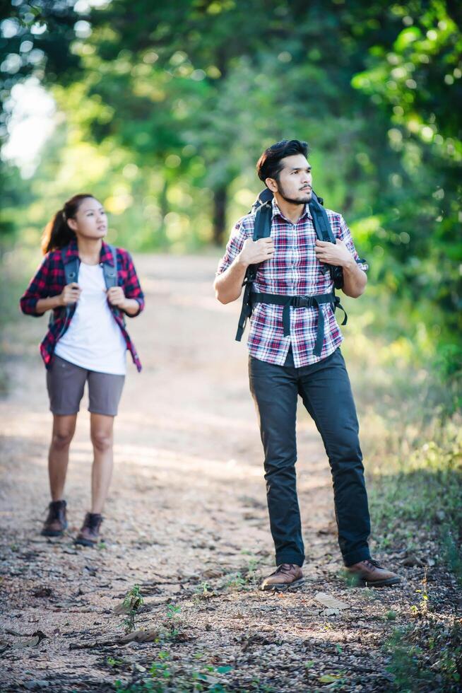 Young couple walking with backpacks in forest. Adventure hikes. photo