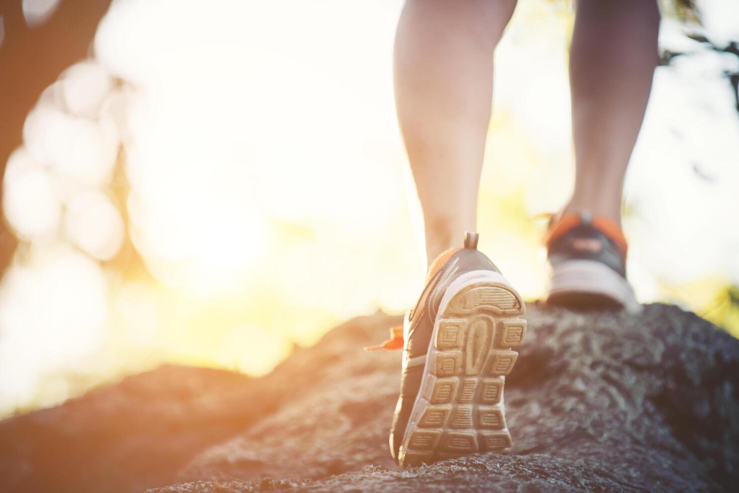 young runner woman legs close-up during running across the rock. photo