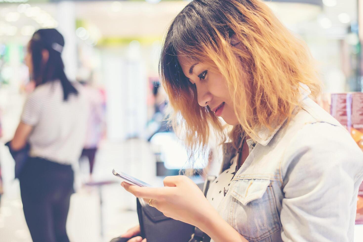 Young beautiful woman texting on the smartphone  in the shopping mall. photo