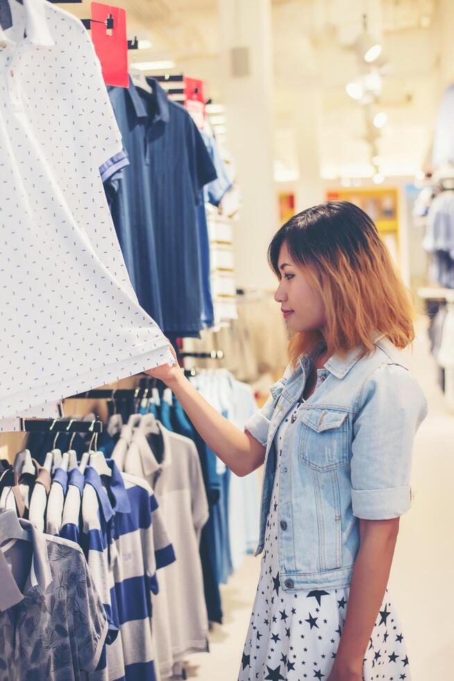 Happy young woman looking at clothes sale in the shop. photo