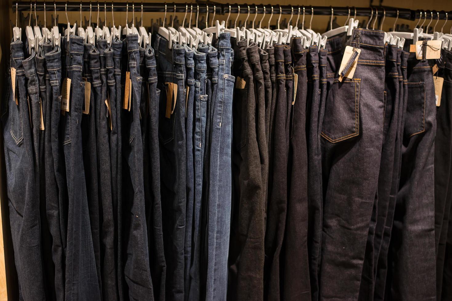 Jeans on clothes rail in clothing store at shopping mall. photo