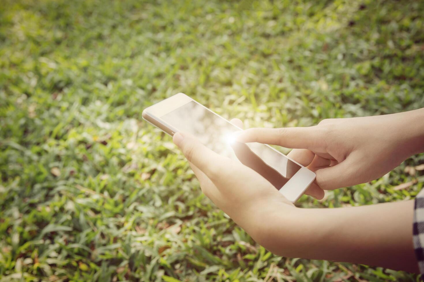 Primer plano de manos de mujer joven con un teléfono inteligente. fondo de la naturaleza. foto