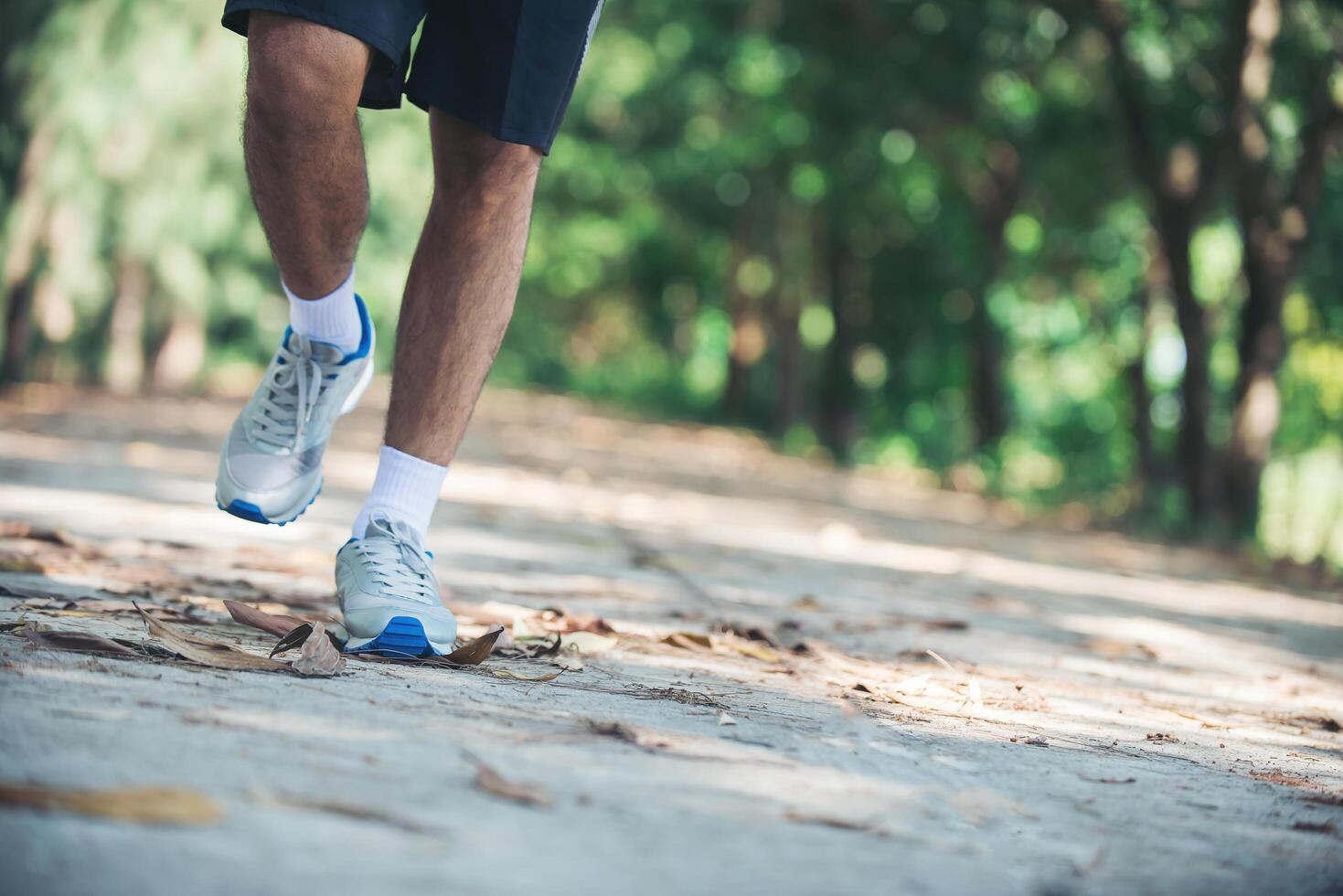 close up foot of young runner man running along road in the park