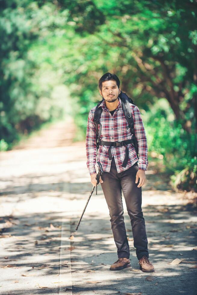 Hipster man hiker holding poles and looking away. photo