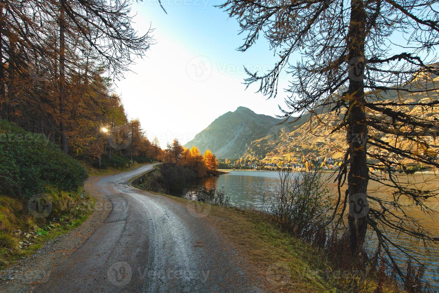 Carretera de montaña aislada cerca del lago en el otoño al atardecer foto
