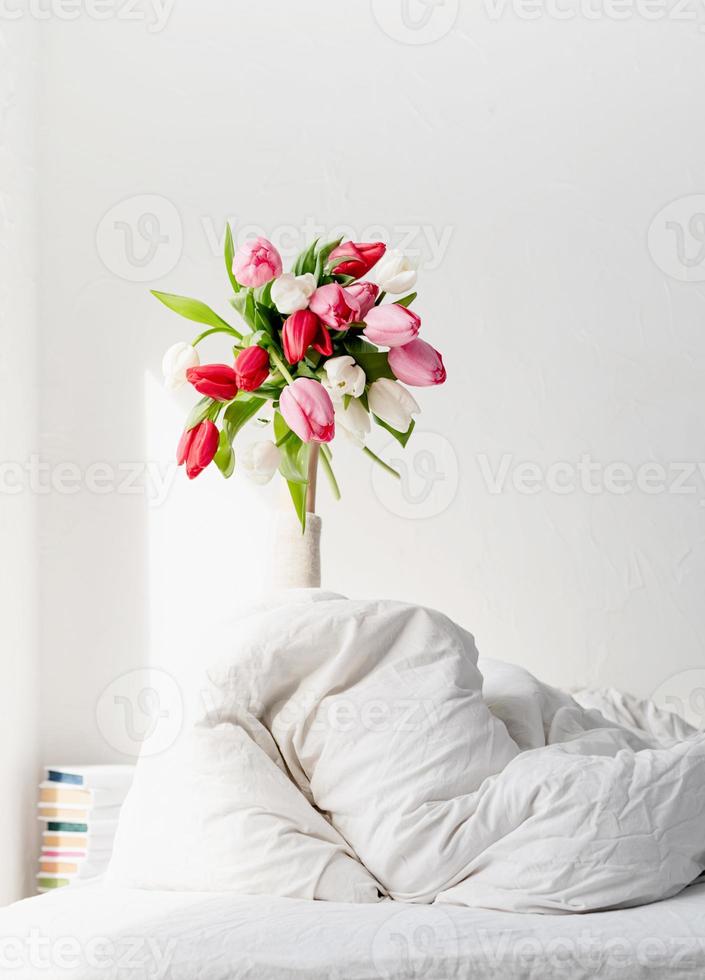 Woman arm outstreched from the blanket holding a bouquet of tulips photo