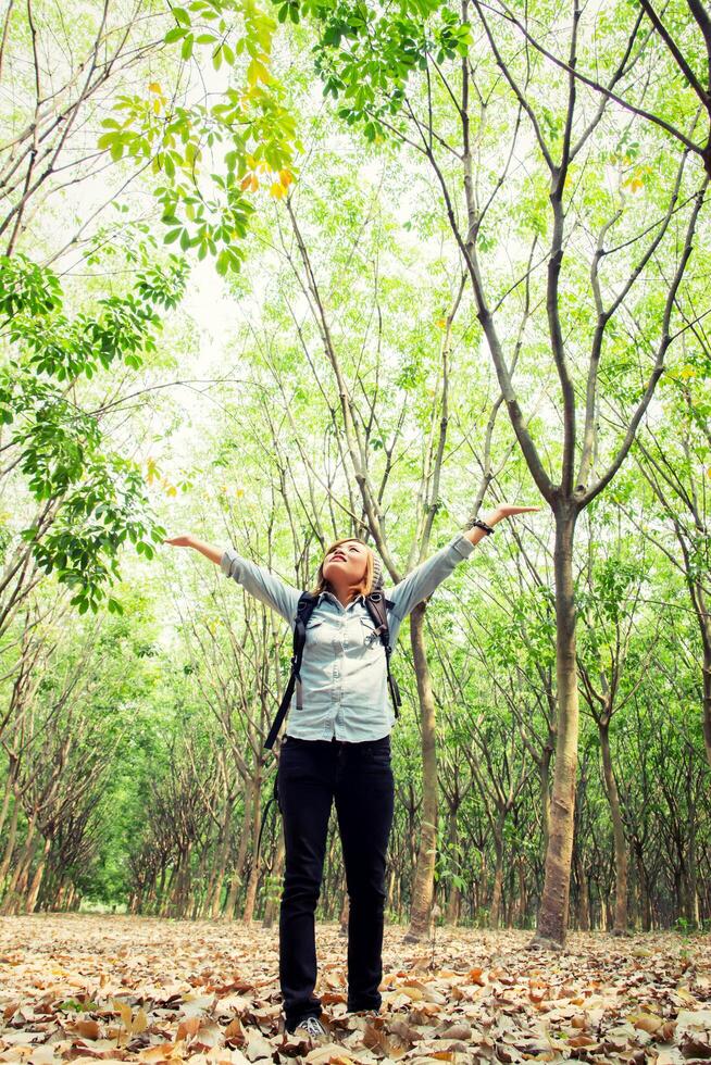 Young woman walking in forest raising her hands happy with fresh air. photo