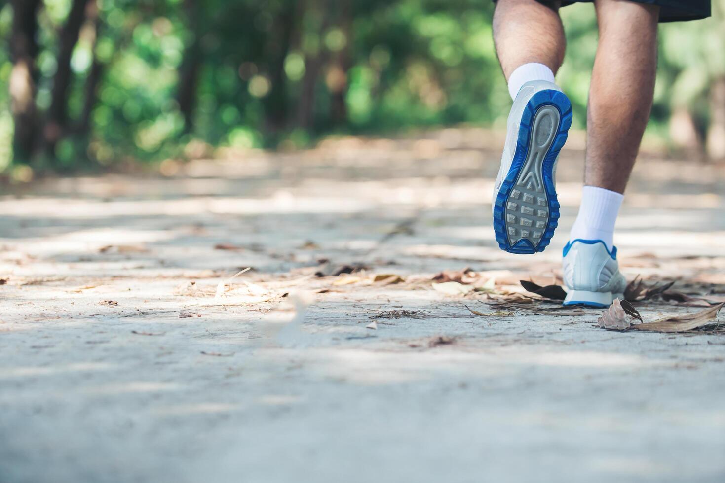 close up foot of young runner man running along road in the park. photo