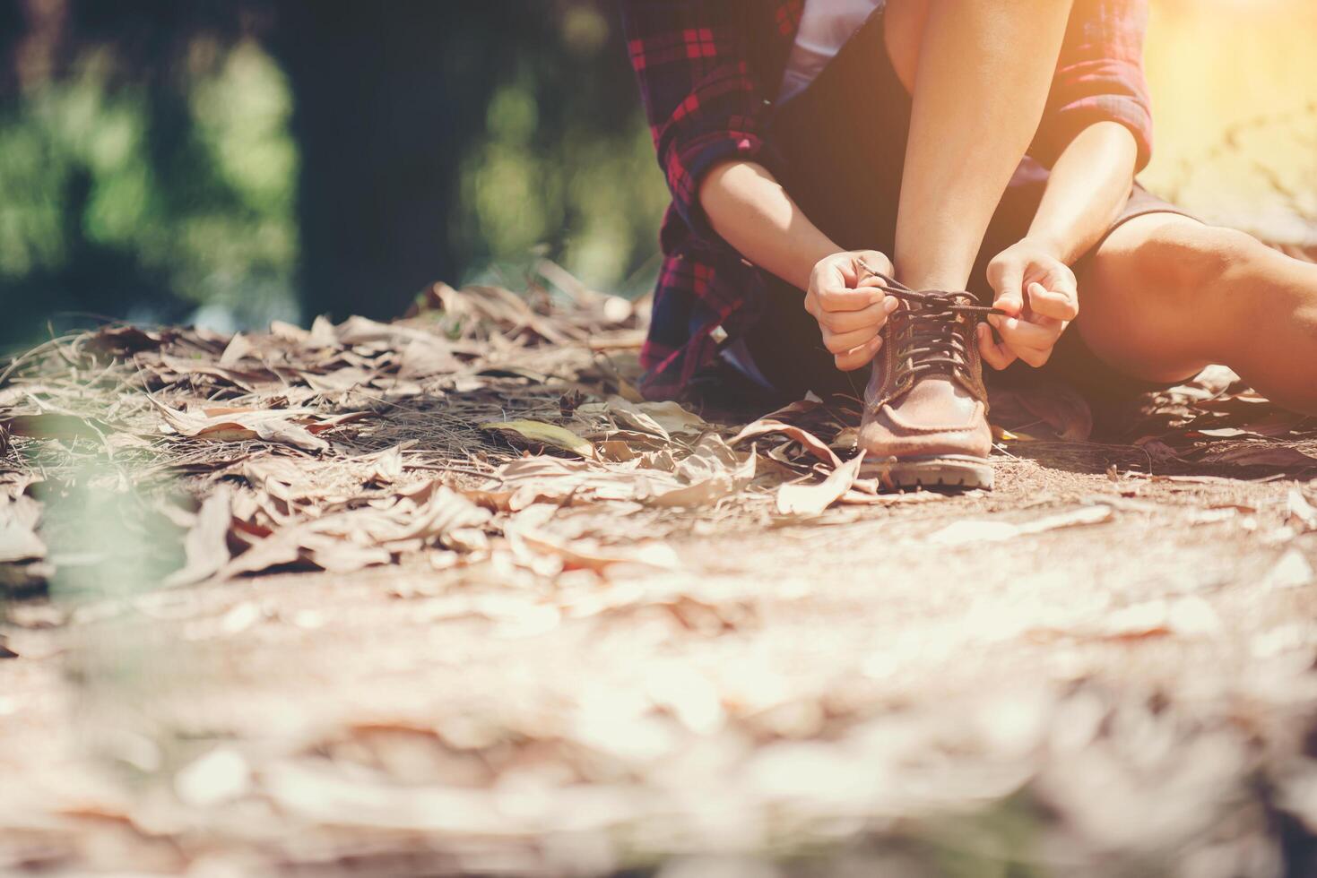 woman hiker stops to tie her shoe on a summer hiking trail in forest. photo