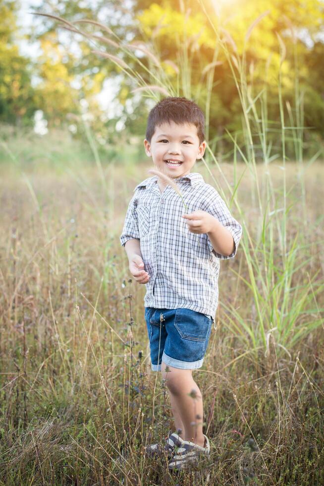 niño asiático feliz jugando al aire libre. lindo chico asiático en el campo. foto