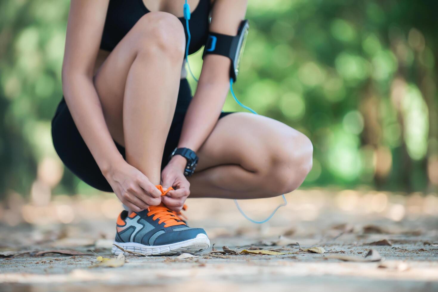 Young beautiful listening to music and tying laces on her shoe. photo