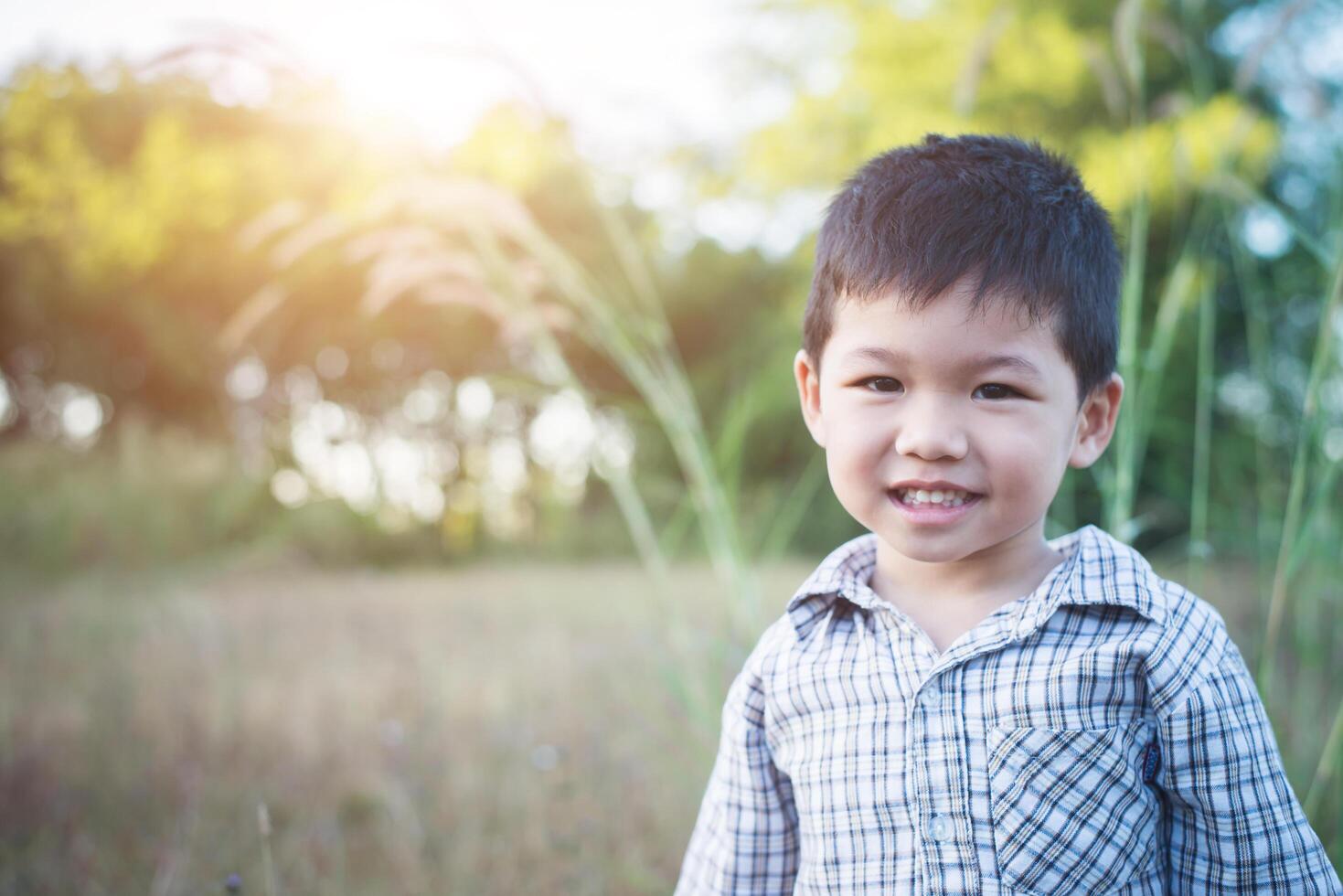 Cerca de lindo chico asiático jugando y sonriendo al aire libre. foto