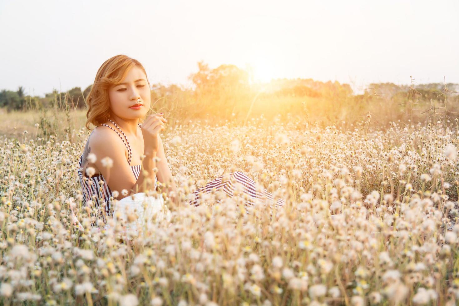 sexy hermosa mujer sentada en el campo de flores disfrutar y oler en flor foto