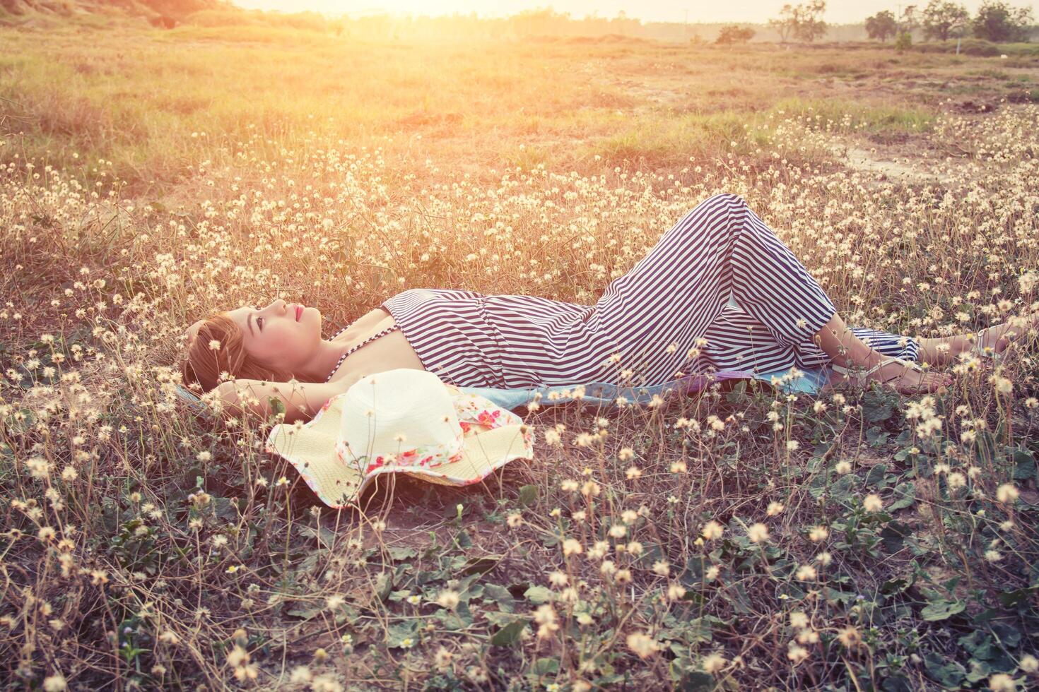 Young sexy woman lying in grass nearing her hat photo