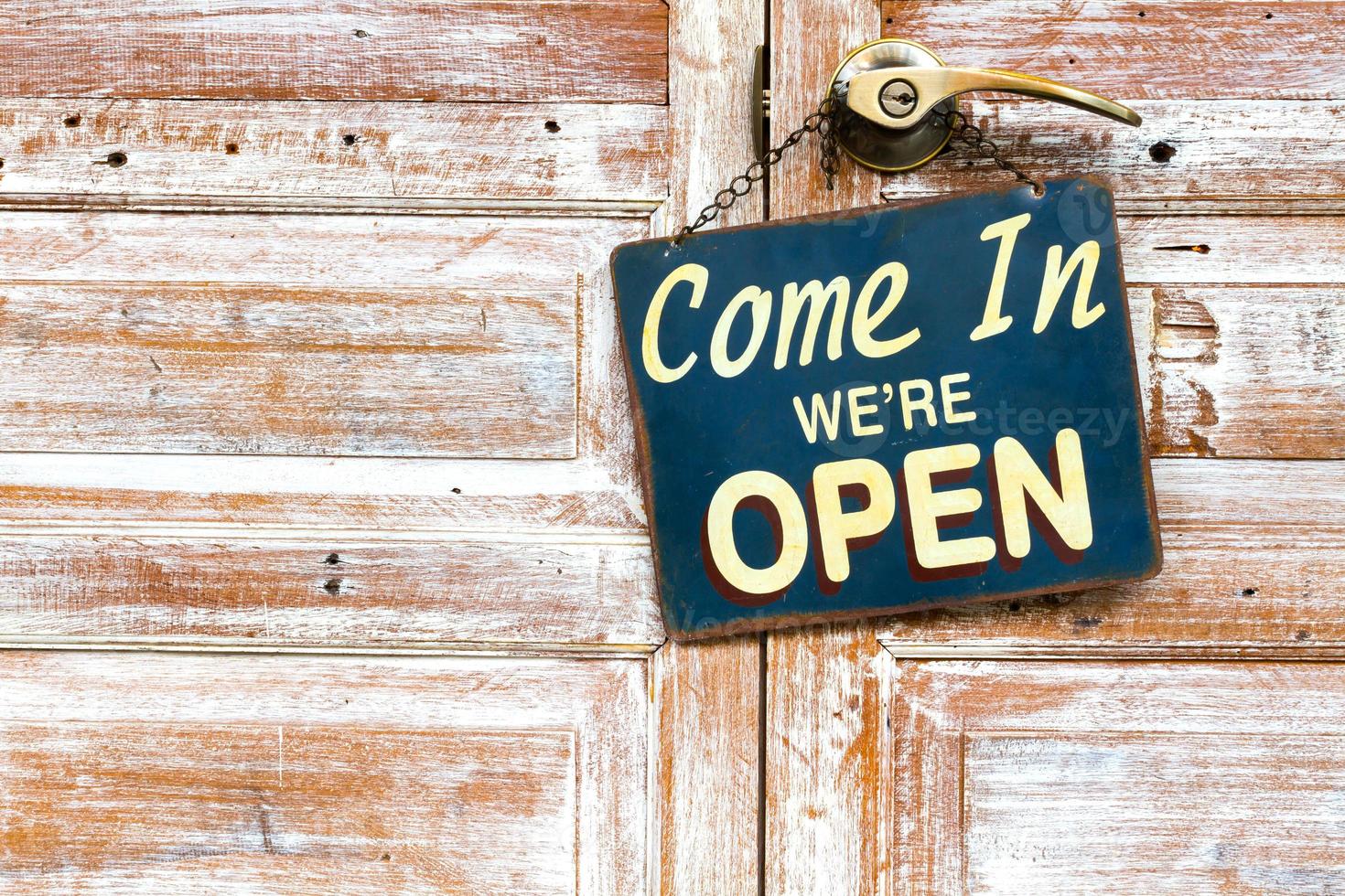 Come In We're Open on the wooden door, copyspace on the left photo