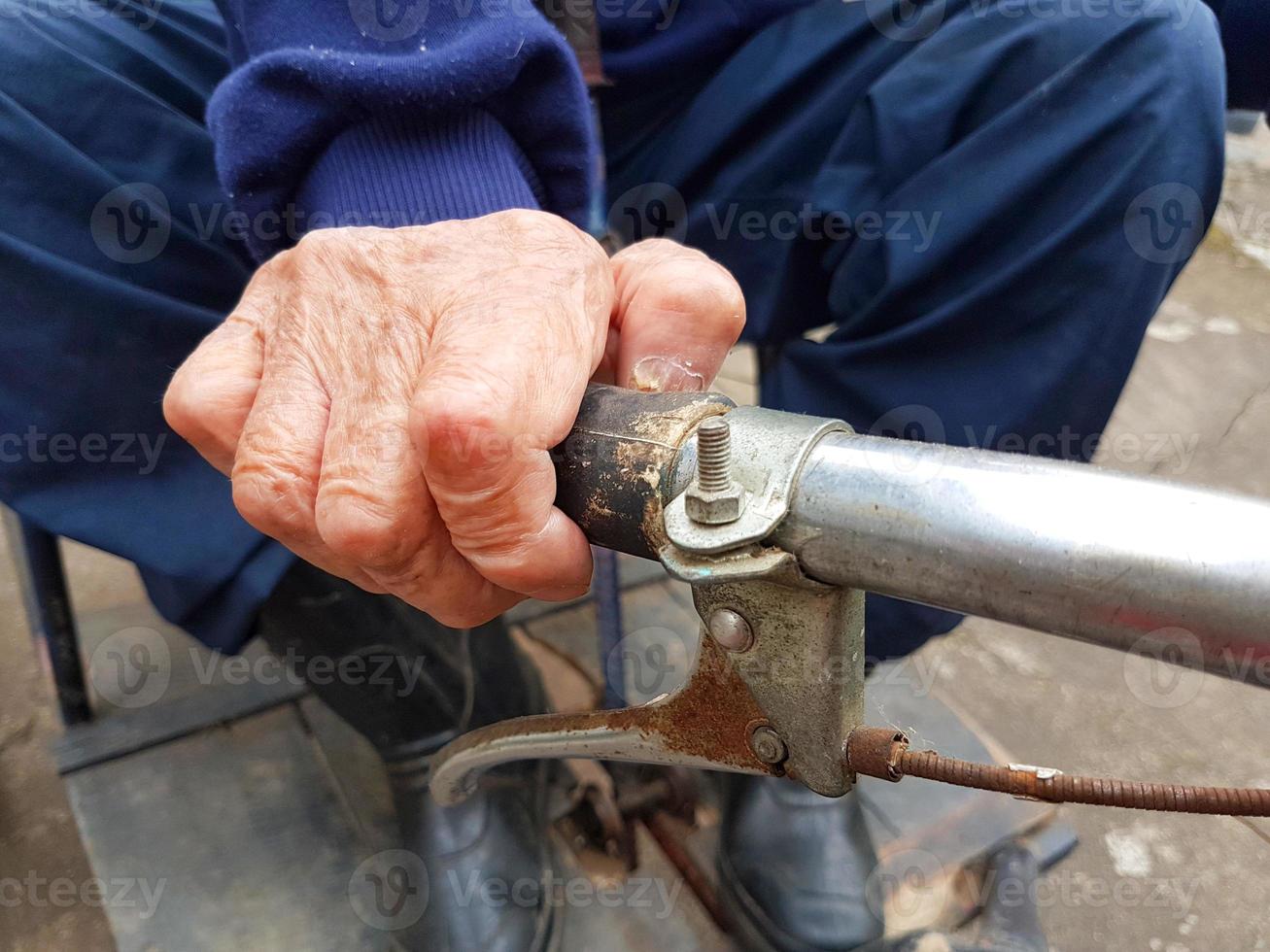 Cerca de la mano del anciano discapacitado sosteniendo la manija del triciclo foto