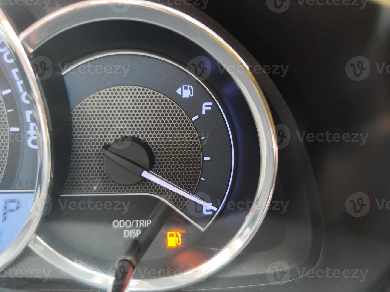 close-up fuel gauge showing empty tank with yellow light glowing photo