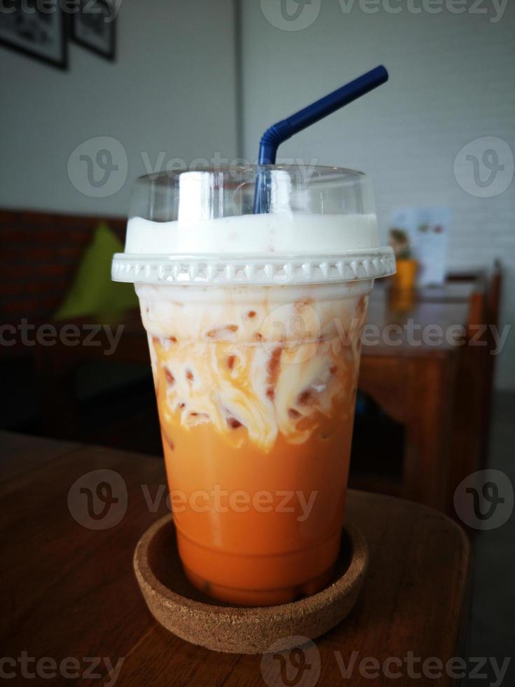 Milk ice tea in takeaway plastic cup on table in cafe, Thailand. photo